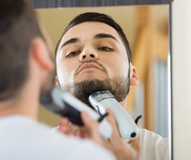 Man shaving beard with trimmer clipart