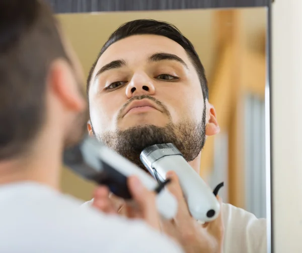 Man shaving beard with trimmer