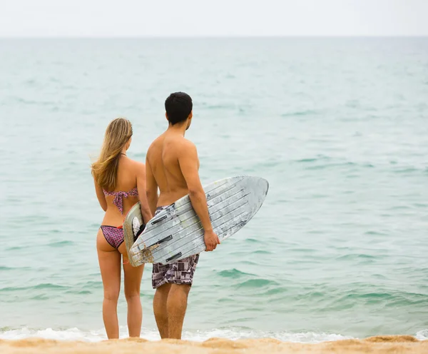 Jovens surfistas casal na praia — Fotografia de Stock