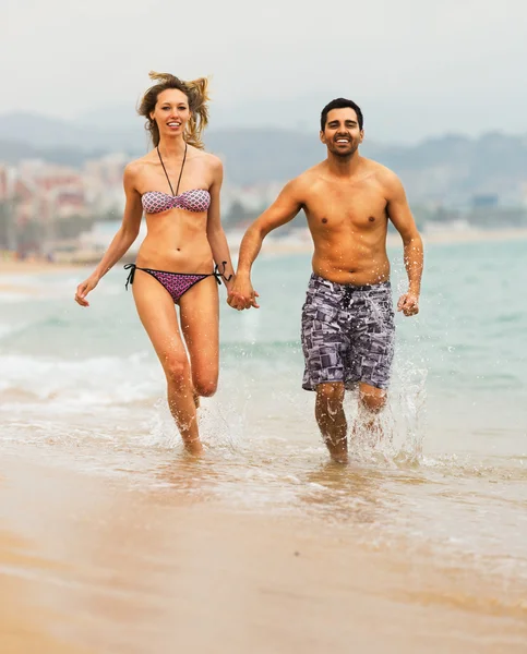 Young couple runs near the sea — Stock Photo, Image