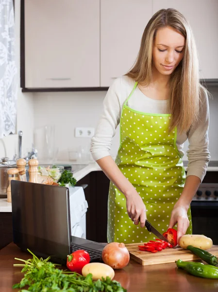 Frau schaut beim Kochen in Laptop — Stockfoto