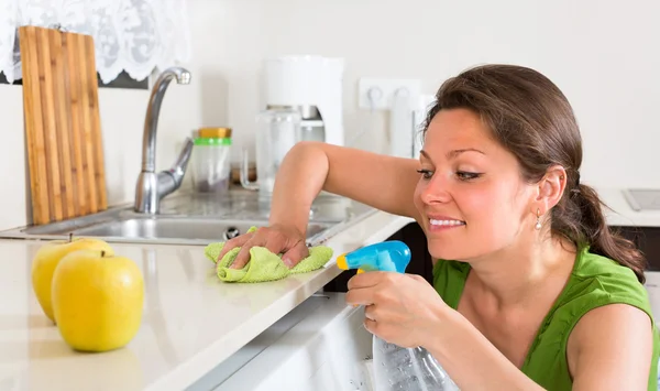 Jeune femme nettoyage dans la cuisine — Photo