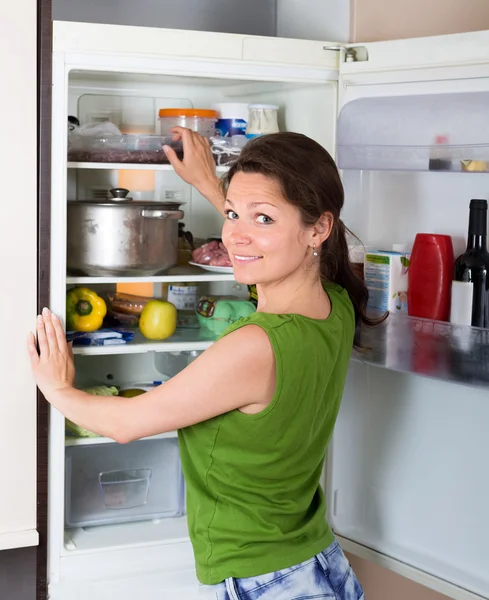 Mujer morena buscando en el refrigerador — Foto de Stock