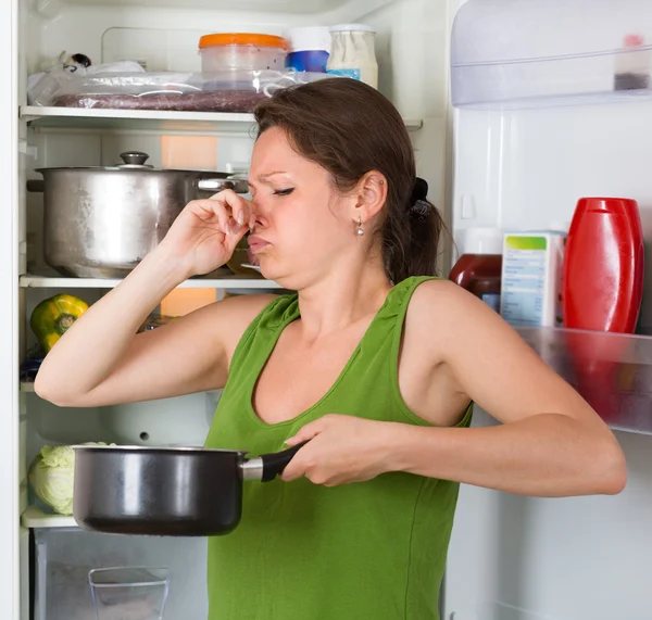 Mulher segurando comida suja perto da geladeira — Fotografia de Stock