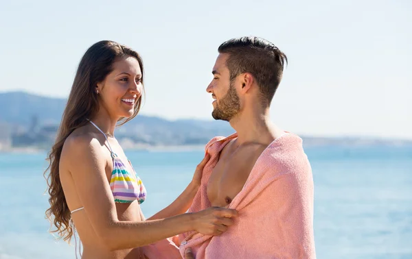 Casal jovem envolto em toalha na praia — Fotografia de Stock