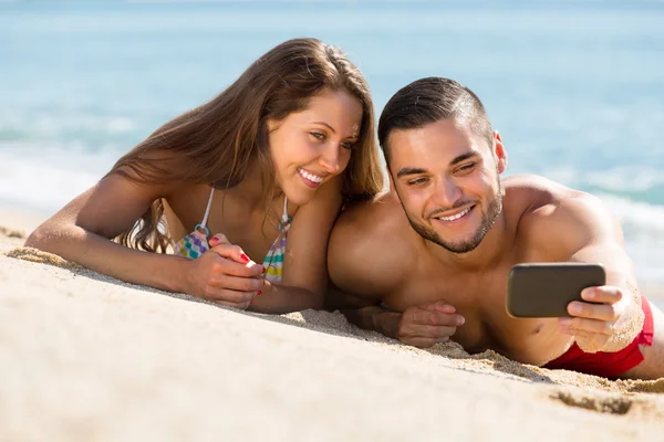 Счастливая пара фотографирует на пляже — стоковое фото