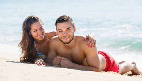 Happy couple resting on sandy beach — Stock Photo, Image