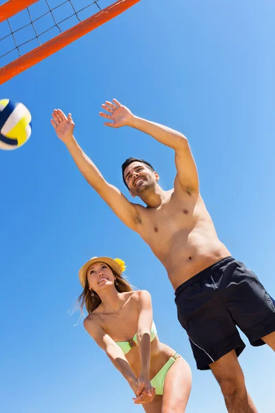 Молодая улыбающаяся пара играет в волейбол — стоковое фото