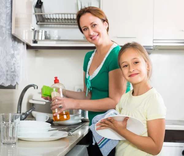 Girl helping mother washing dishes Stock Photo