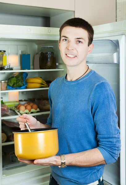 Man med kastrull nära kylskåp — Stockfoto