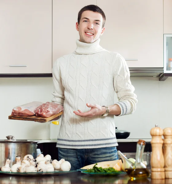 Homem segurando carne na cozinha — Fotografia de Stock