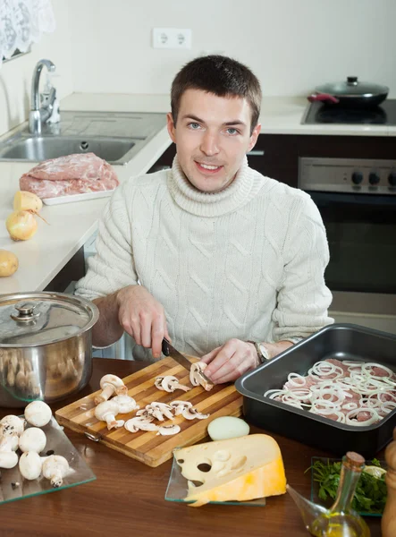 Homem cozinhar carne com cogumelos e batatas — Fotografia de Stock