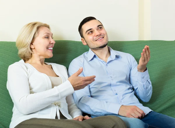 Young man and aged woman talking indoor — Stock Photo, Image