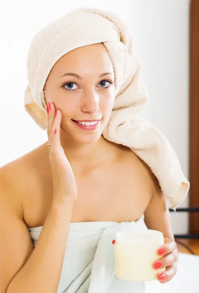 Mujer joven poniendo crema en la cara — Foto de Stock