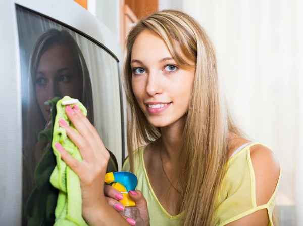 Mulher loira limpando TV em casa — Fotografia de Stock