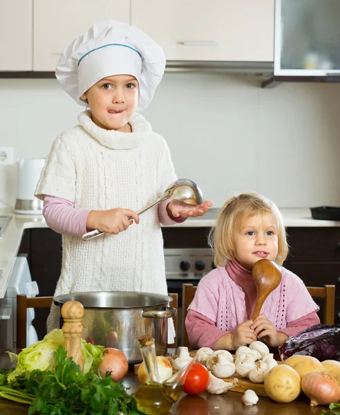 Två små systrar som lär sig laga mat — Stockfoto