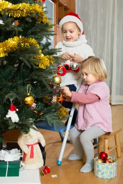 Två små flickor dekorera julgran — Stockfoto