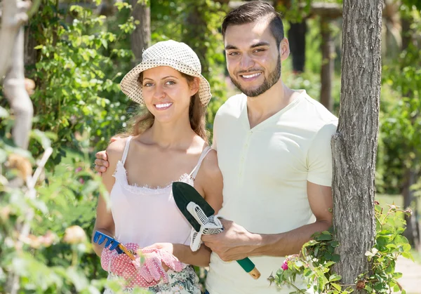 Cheerful married couple in flowers garden — Stock Photo, Image