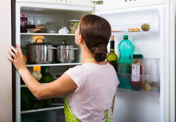 Ama de casa cerca nevera llena — Foto de Stock