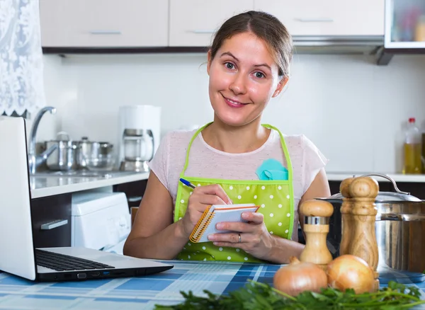 Frau macht Einkaufsliste in der Küche — Stockfoto