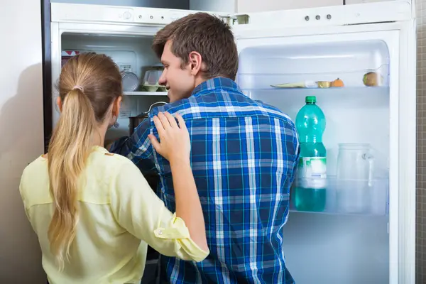 Man and woman standing near fridge — Stock Photo, Image