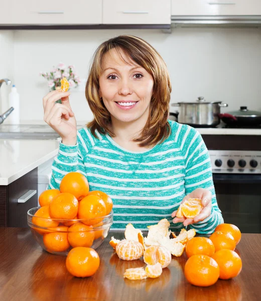 Mulher sorrindo comer tangerinas — Fotografia de Stock