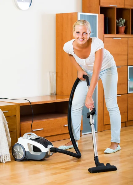 Housewife vacuuming floor and furniture — Stock Photo, Image