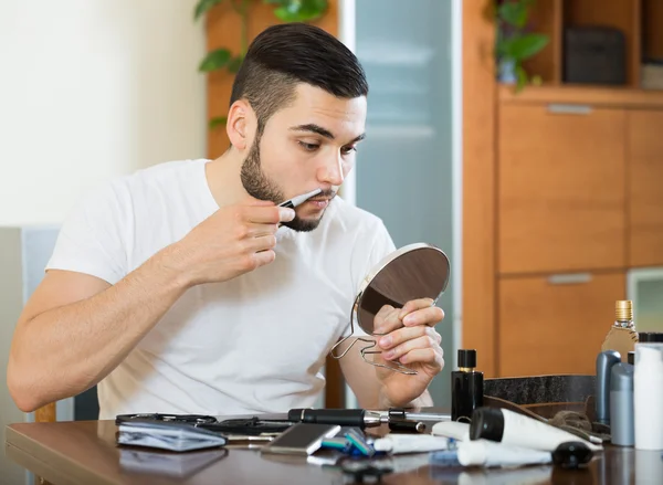 Guy rakning skägget med trimmern — Stockfoto