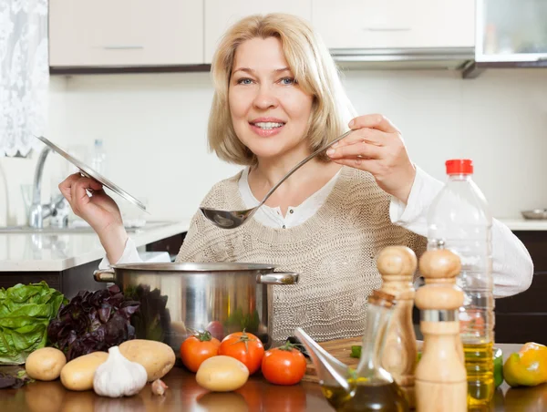 Gelukkig volwassen vrouw soep koken — Stockfoto