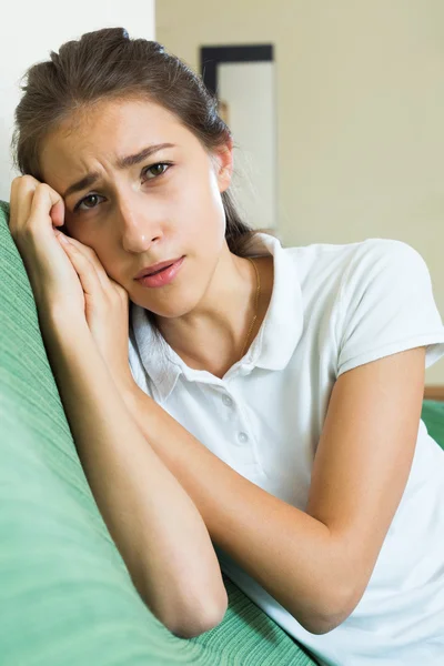 Расстроенная девушка на диване дома — стоковое фото