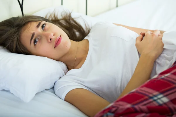 Retrato de menina morena na cama com dor de estômago — Fotografia de Stock