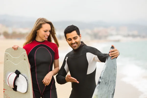 Couple avec planches de surf sur la plage — Photo