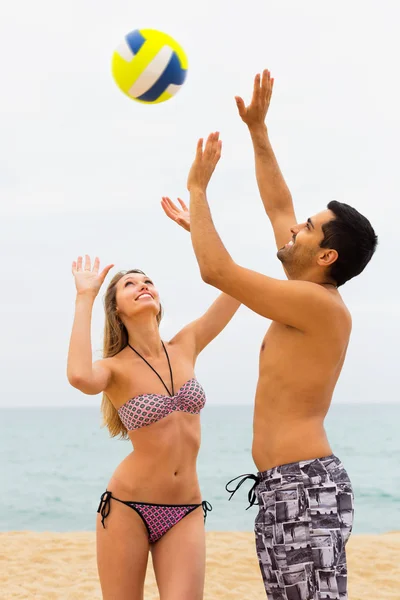 Gelukkige paar spelen met een bal op strand — Stockfoto