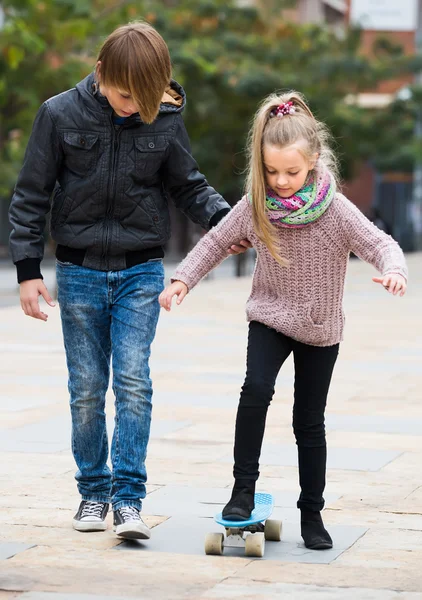 Teenager teaching sister skateboarding — Stock Photo, Image