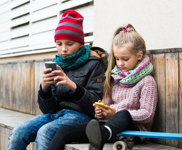 Niños mirando teléfonos inteligentes — Foto de Stock