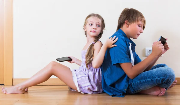 Niños jugando en teléfonos móviles — Foto de Stock