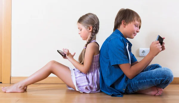 Kinderen spelen in mobiele telefoons — Stockfoto