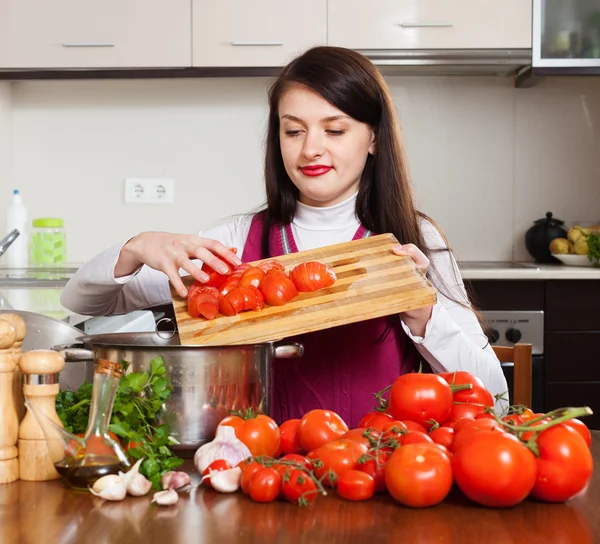 Jonge huisvrouw koken met tomaten — Stockfoto