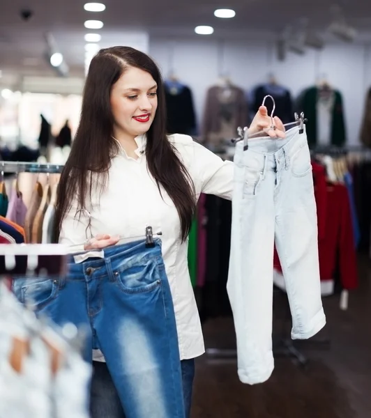 Flickan att välja byxor i butik — Stockfoto