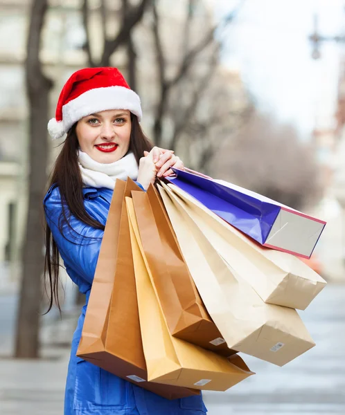 Femme heureuse en chapeau de Père Noël avec des achats — Photo