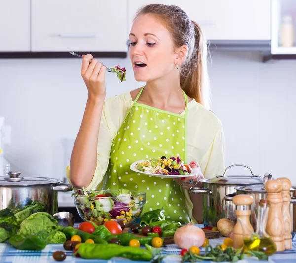 Kvinna äter hälsosam sallad i köket — Stockfoto