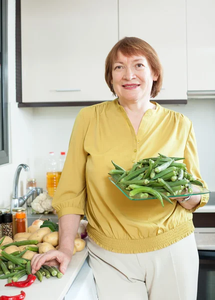 Mulher com quiabo na cozinha — Fotografia de Stock