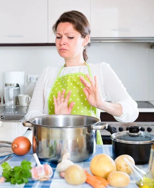 Huisvrouw kijken naar bedorven voedsel in pan — Stockfoto