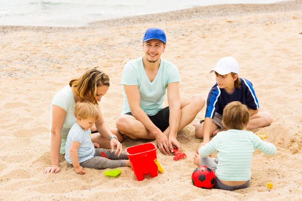 Familjen av fem sitter vid sandstrand — Stockfoto