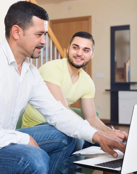 Два взрослых мужчины с ноутбуком в помещении — стоковое фото