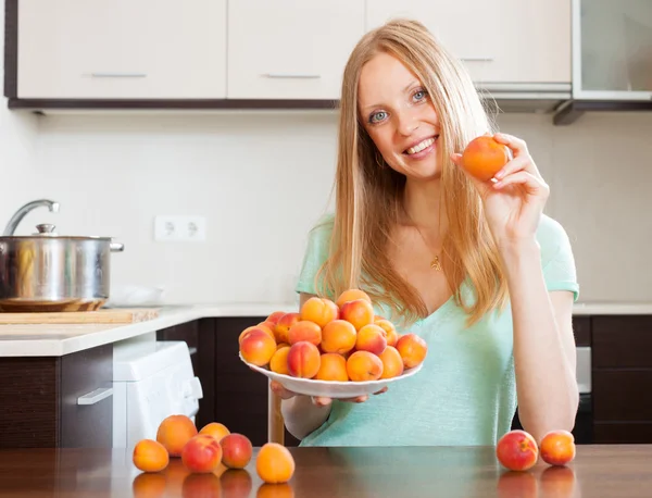 Blond flicka nära upplag av aprikoser — Stockfoto