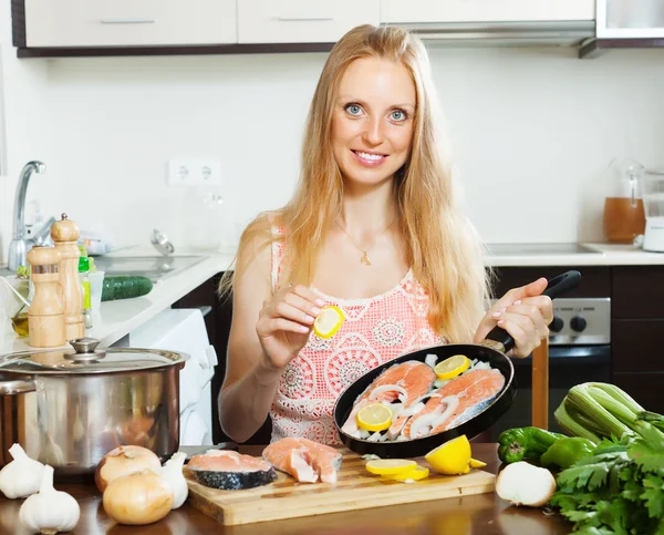 Žena vaření losos s citronem na pánvi — Stock fotografie