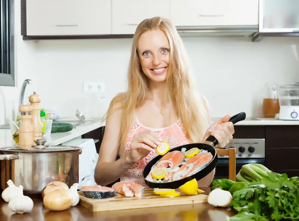 Donna sorridente cucina pesce salmone con limone — Foto Stock