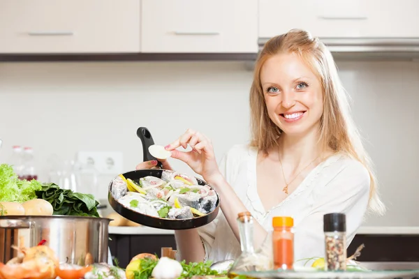 Chica cocinar pescado en sartén en la cocina — Foto de Stock