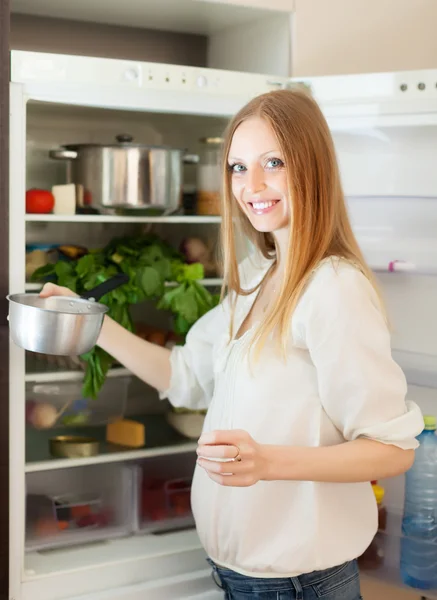 Frau mit Pfanne nahe geöffnetem Kühlschrank — Stockfoto